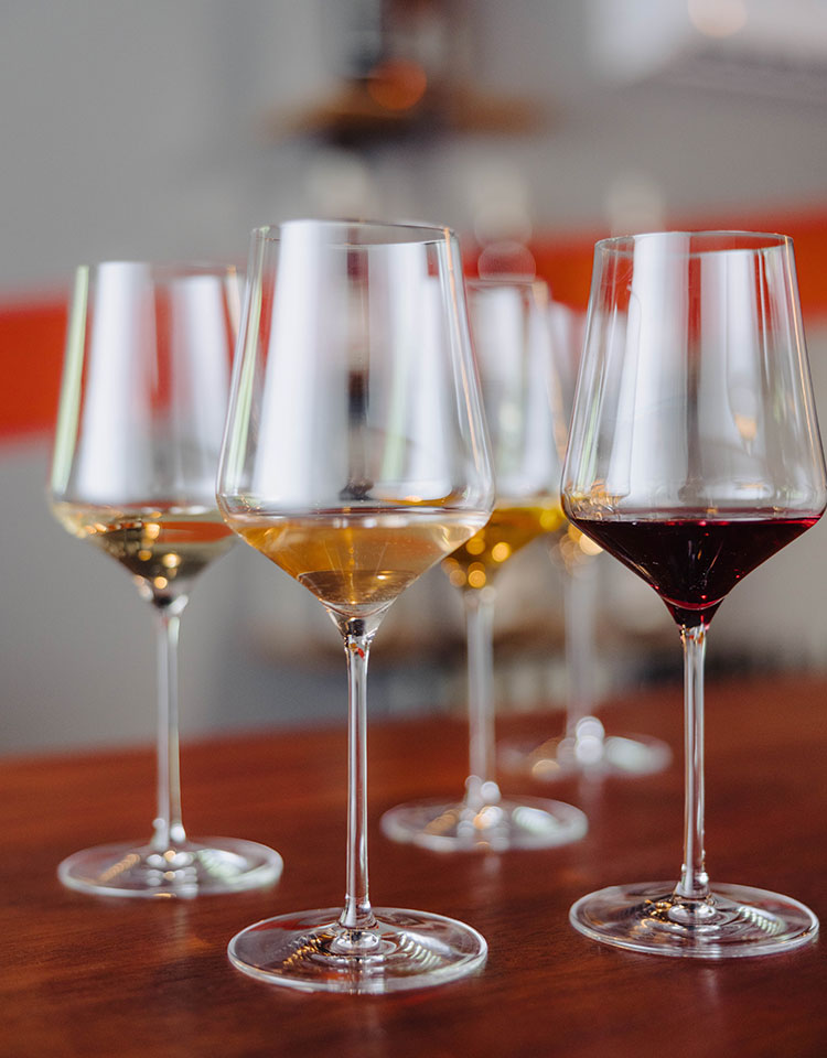 A cluster of wine tasting glasses filled with wine.